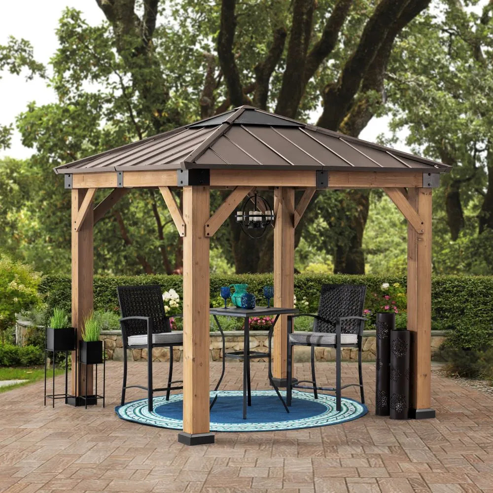Wooden gazebo with a metal roof in an outdoor setting with chairs and a table.