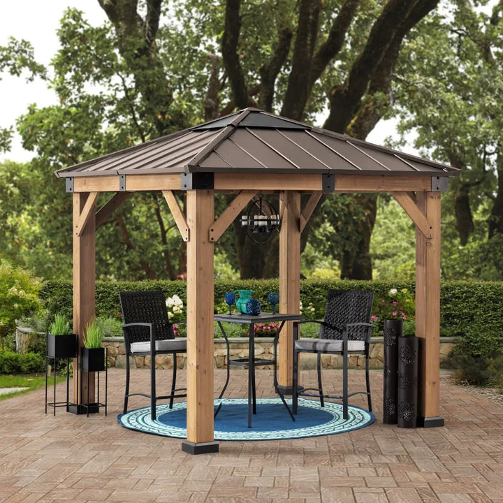 Wooden gazebo with a metal roof in an outdoor setting with chairs and a table.