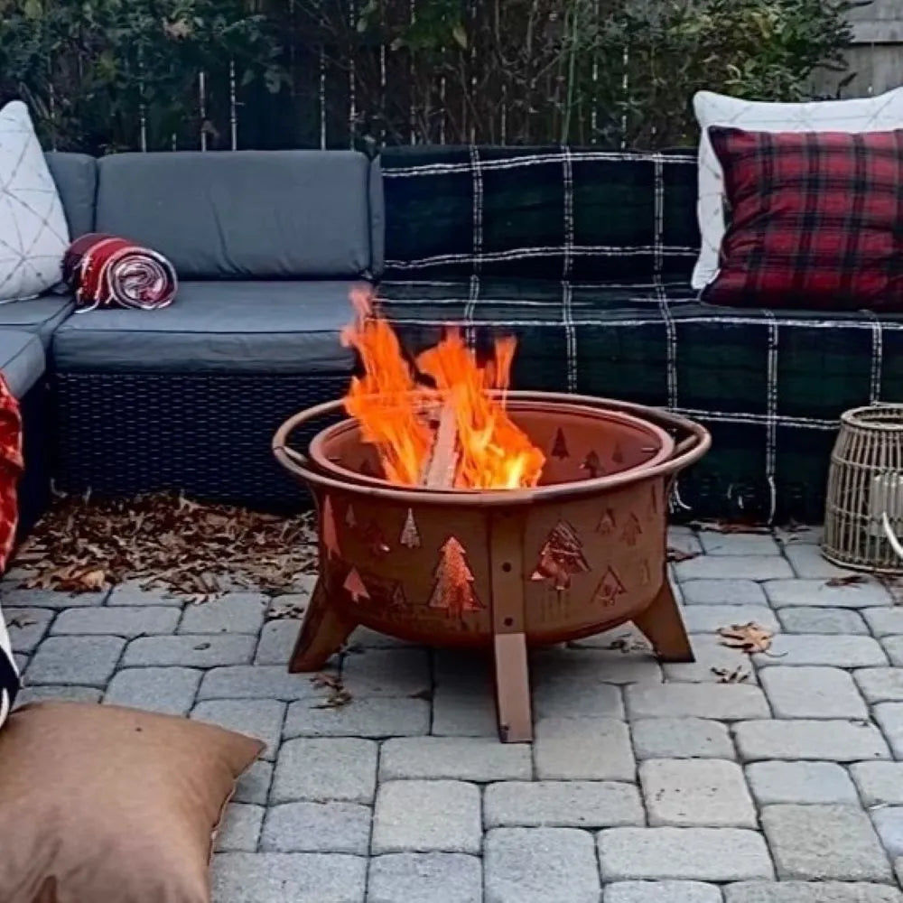 Fire pit with flames in a backyard setting with a couch and pillows.