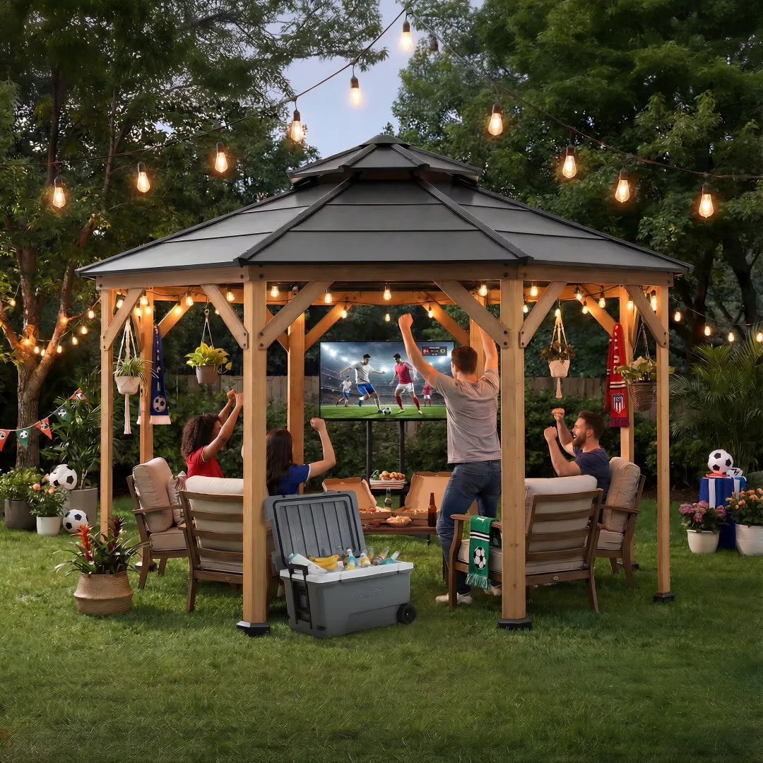 People watching sports on a screen in a backyard with a wooden gazebo and string lights.