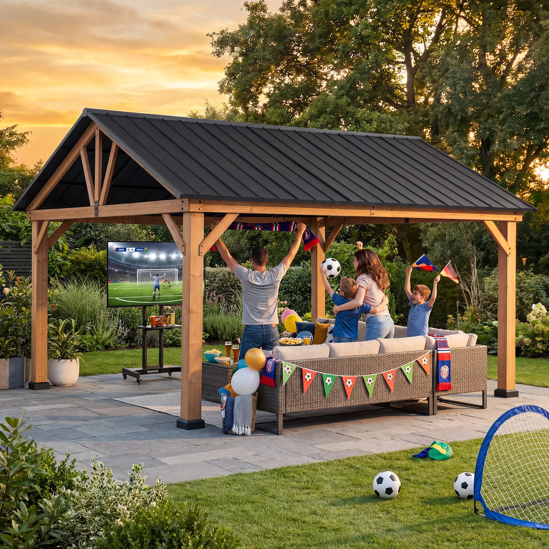 People sitting under a wooden gazebo watching a screen outdoors.