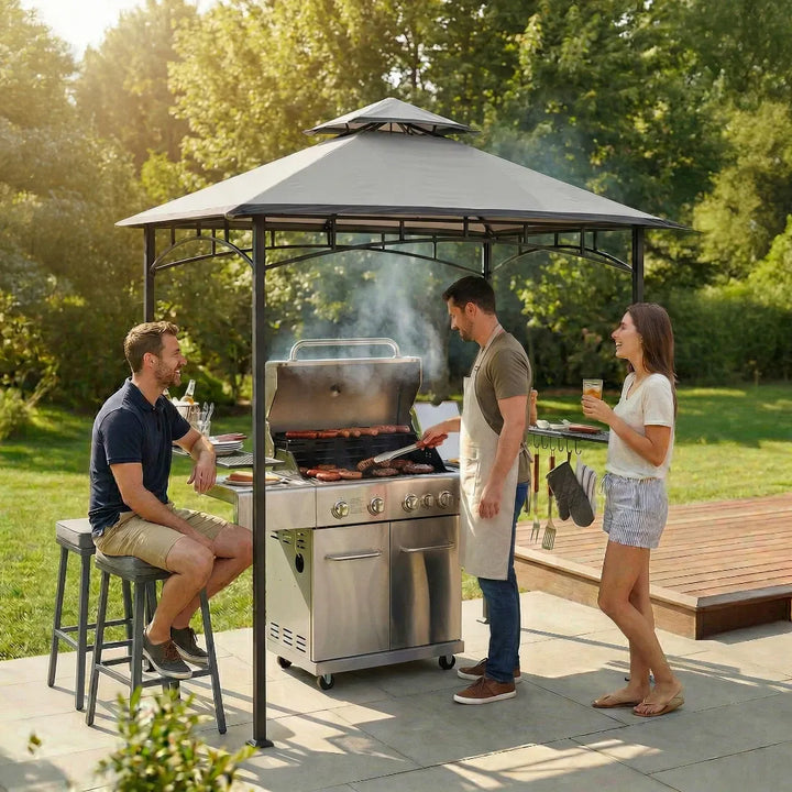 People grilling outdoors with a gazebo and trees in the background